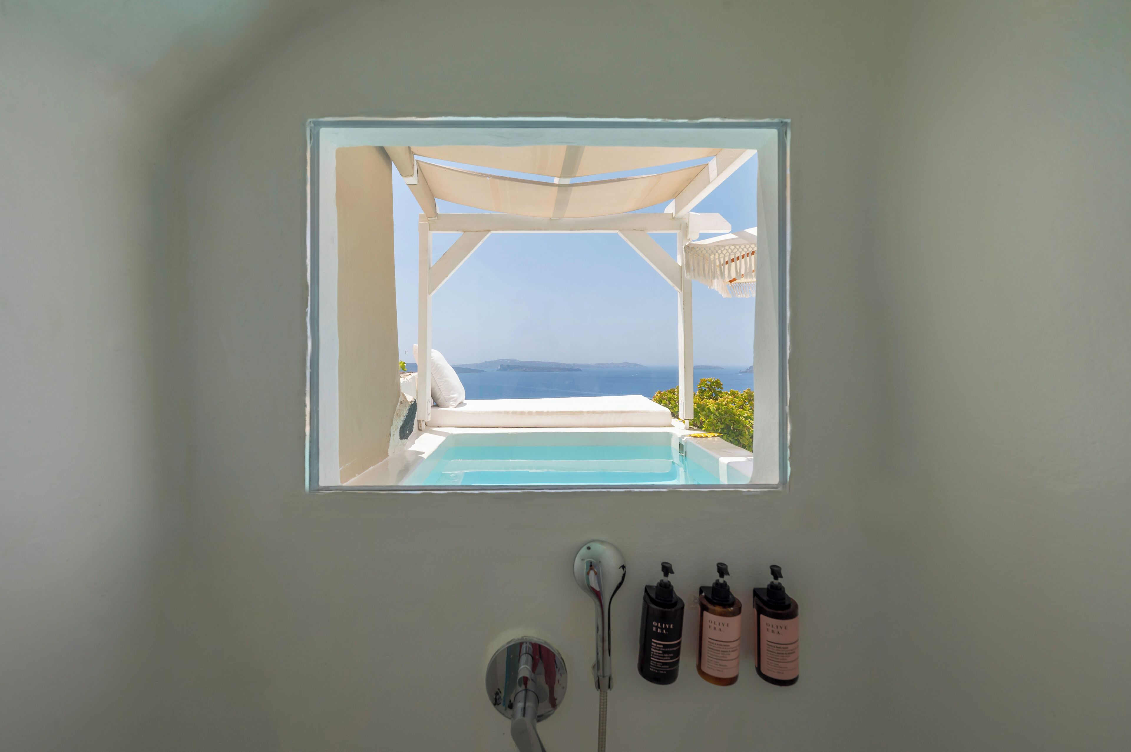 Une salle de bain avec vue sur la piscine et la mer, une douche et deux bouteilles de shampoing.