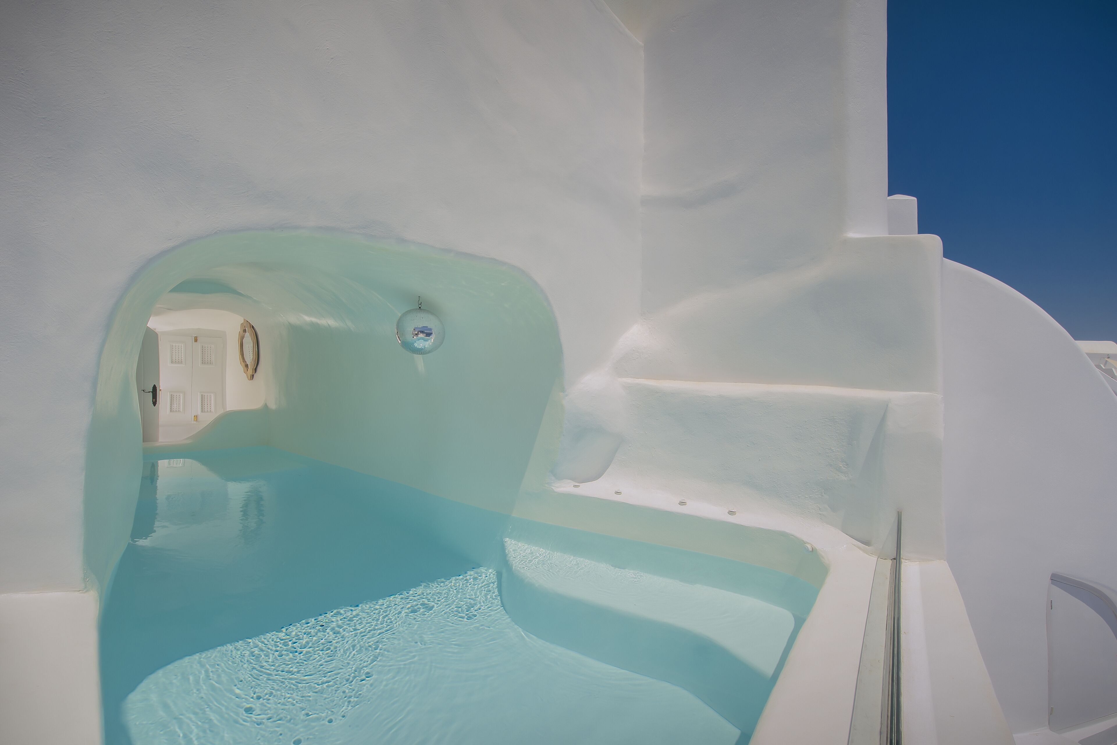 A modern, minimalist bathroom with a large bathtub and a clear view of the adjacent room.