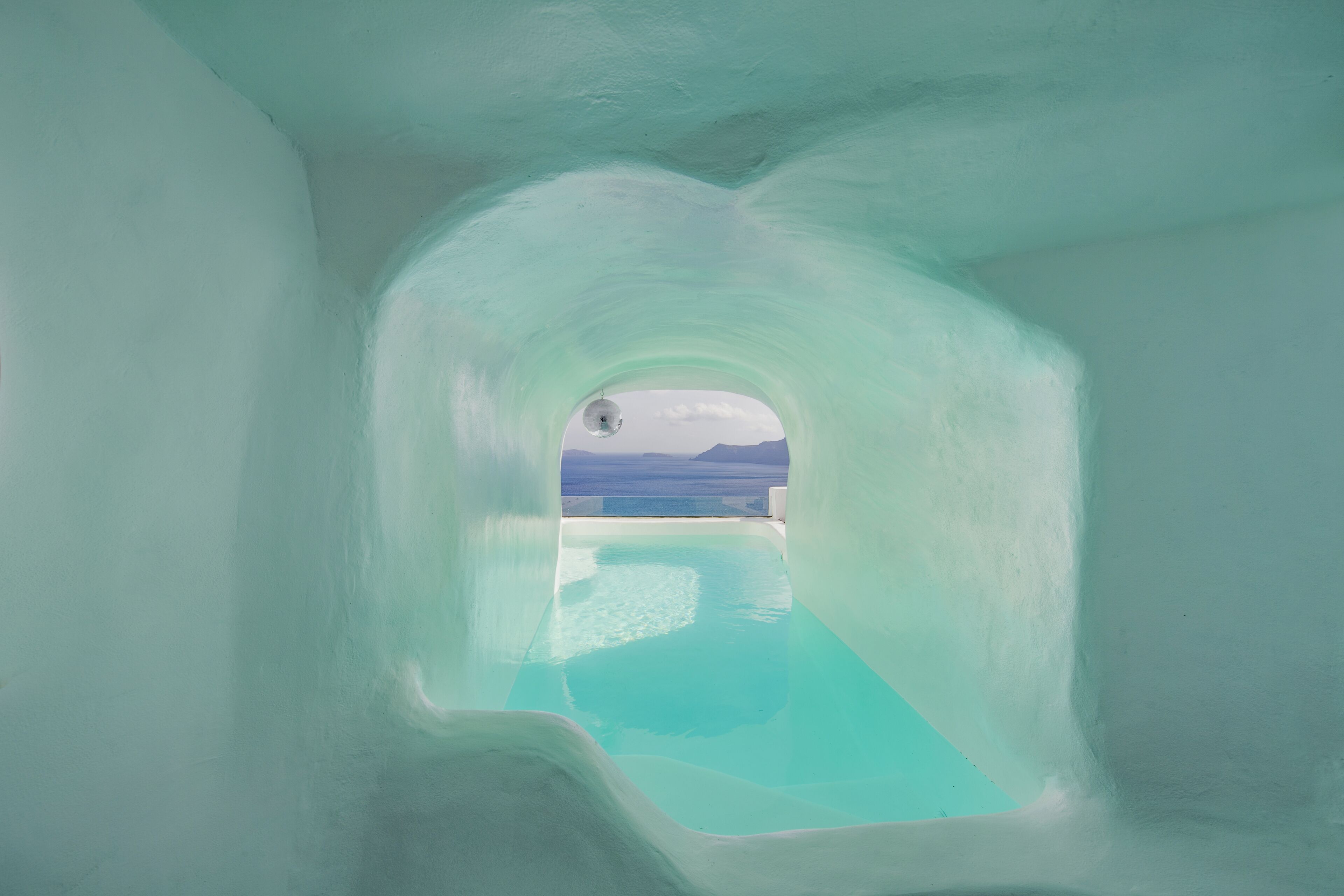 An ice-like structure with a pool and a view of the sky and distant landscape.