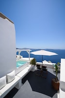 Una terraza en la azotea con piscina, mobiliario blanco y vistas al mar.