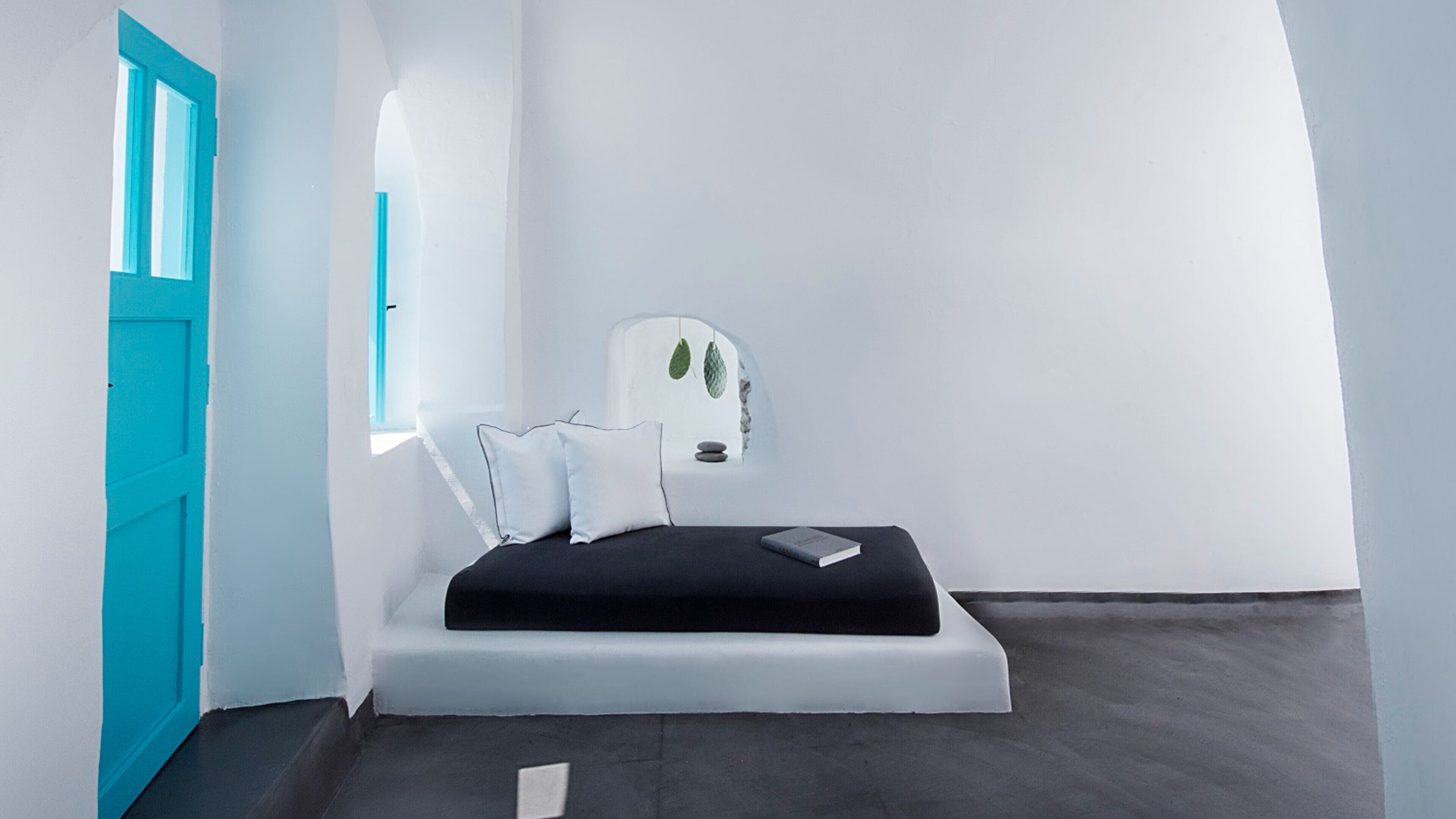 A minimalist bedroom with a bed, pillows, and a book.