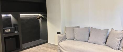 Una sala de estar moderna con un sofá gris, un mueble de entretenimiento negro y piso de madera.