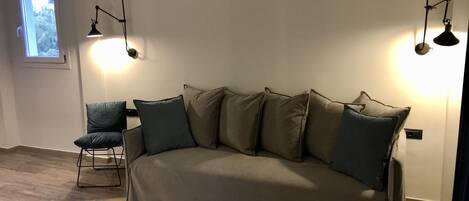 A modern living room with a beige sofa, a small side table, and two floor lamps.