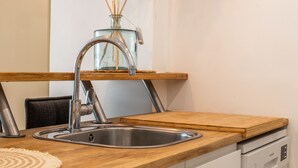 A kitchen with a stainless steel sink, wooden countertop, and a dish rack.