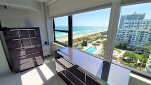 A modern hotel room with a large window offering a view of a beach and a pool. - Magnificent Modern Direct Oceanfront 3 Bedroom - 1401 (Miami Beach)