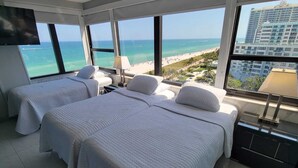 A hotel room with two beds, a TV, and a view of the beach and ocean. - Magnificent Modern Direct Oceanfront 3 Bedroom - 1401 (Miami Beach)