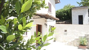 A white building with a stone wall and a wooden door.