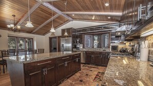A spacious kitchen with granite countertops, dark wooden cabinets, and a large island. - Highlands Lodge by Hauserman Rental Group (Tahoe City)