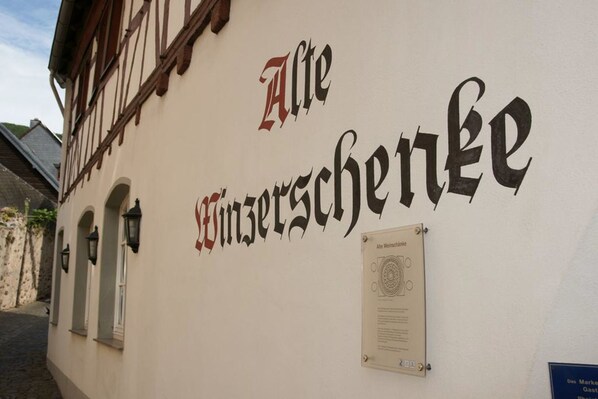 A building with the sign "Alte Wiesenstraße" in large, decorative lettering. There is a small plaque with text and a logo on the wall. - Alte Winzerschenke Ferienweingut (Bruttig-Fankel)