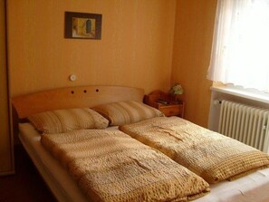 A double bed with a wooden headboard, a bedside table with a lamp, and a radiator. - Alte Winzerschenke Ferienweingut (Bruttig-Fankel)