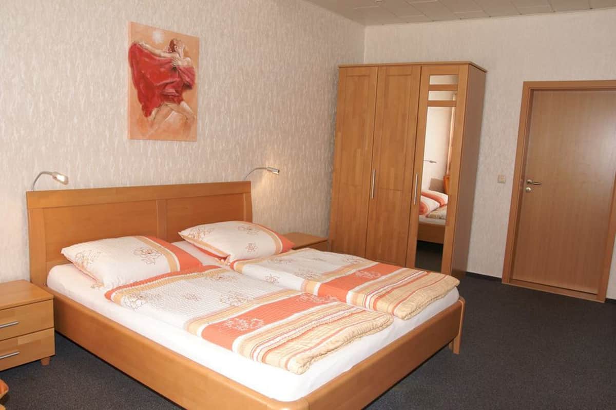 A bedroom with a wooden bed, a nightstand, a wardrobe, and a painting on the wall.