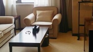 Une chambre d’hôtel avec un canapé, une petite table, une lampe et une fenêtre avec des rideaux.