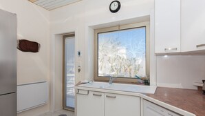 A modern kitchen with a built-in dishwasher, a window with a view of trees, and a clock on the wall. - Sea View, Cannes Croisette, in Front of the Sea (Cannes)
