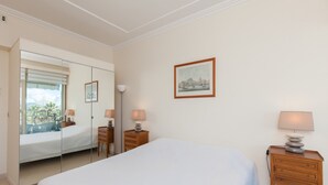 A hotel room with a large bed, a bedside table with lamps, a mirror, and a framed picture on the wall. - Sea View, Cannes Croisette, in Front of the Sea (Cannes)