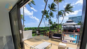 A deck with a pool, palm trees, and a gazebo.