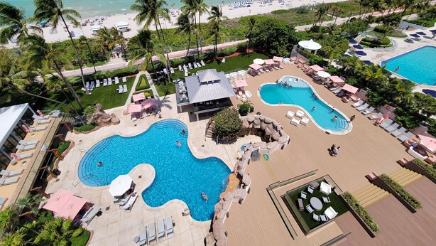 A resort with multiple swimming pools, sun loungers, and a beach area.