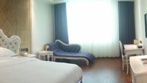 A hotel room with a large bed, a desk, a chair, and a sofa. - Chenmao Yuyang Hote (Guigang)