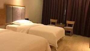 A hotel room with two beds, a wooden headboard, a small table, and a chair. - Chenmao Yuyang Hote (Guigang)