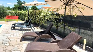 Buitenteak fauteuils, een zwembad en parasols.
