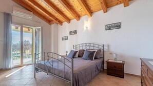 Een slaapkamer met een bed, nachtkastje, kaptafel en uitzicht op het omliggende landschap.