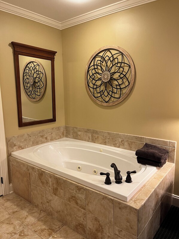 A bathroom with a large bathtub, two faucets, and a towel on the side.