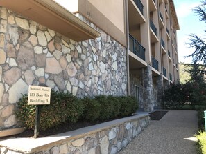 A stone facade with a sign for Summit Manor, Building A, and a multi-story building with balconies.
