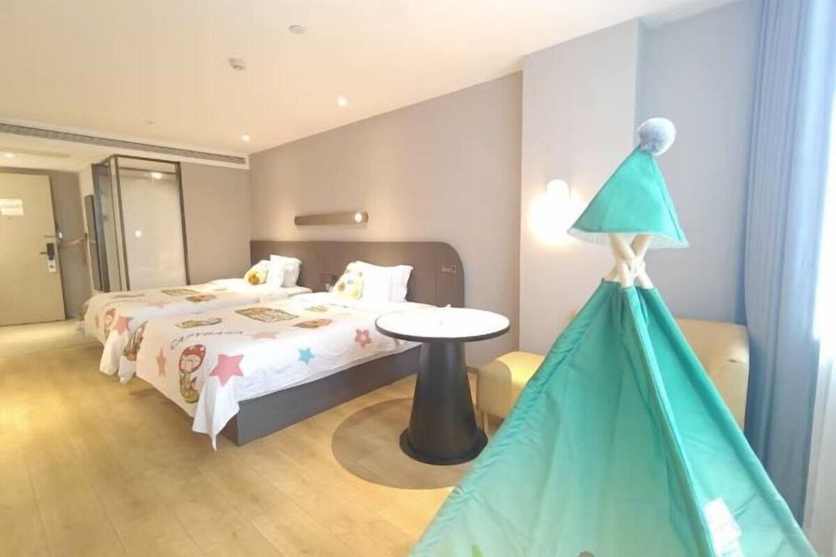 Una habitación de hotel con una cama, una mesa redonda y un maniquí.