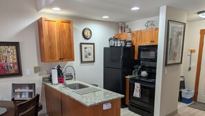 A modern kitchen with wooden cabinets, a granite countertop, a black refrigerator, a stove, and a sink. - Our studio condo is the closest condo to the Eagle Lift.  Just steps away. (Frisco)