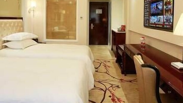 A hotel room with a bed, a desk, a chair, and a wall-mounted TV. - Modern Square Hotel (Lishui)