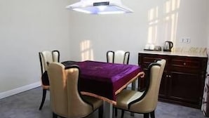A dining area with a table and chairs, a pendant light, and a kitchen area in the background. - Modern Square Hotel (Lishui)