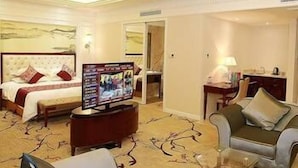 A hotel room with a bed, a TV, a sofa, and a coffee table. - Modern Square Hotel (Lishui)