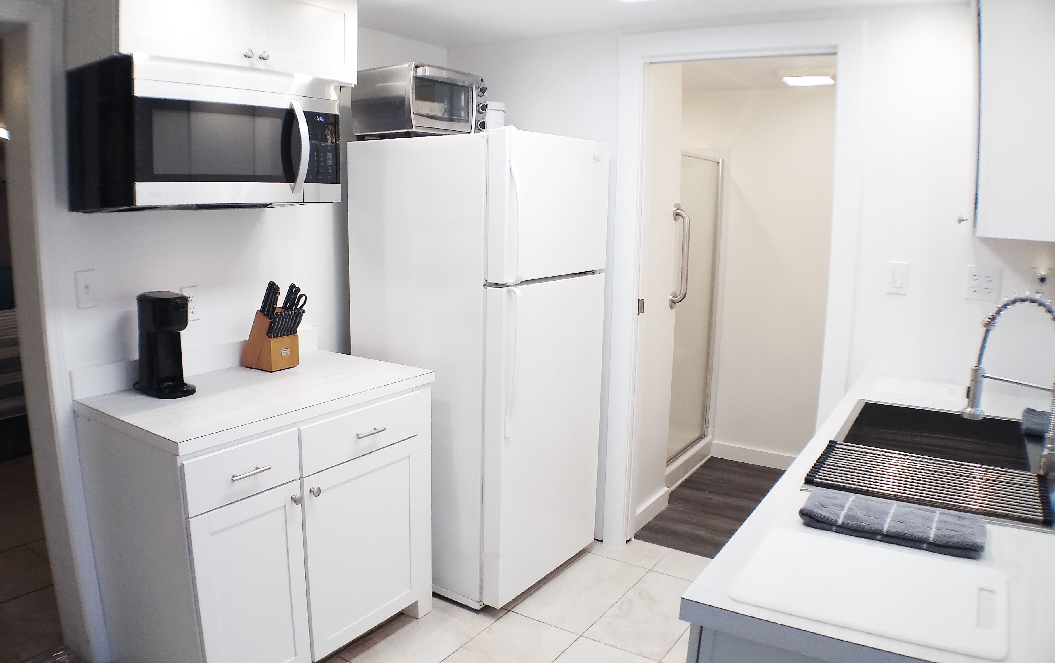 A modern kitchen with white cabinetry, a microwave, a refrigerator, and a sink.