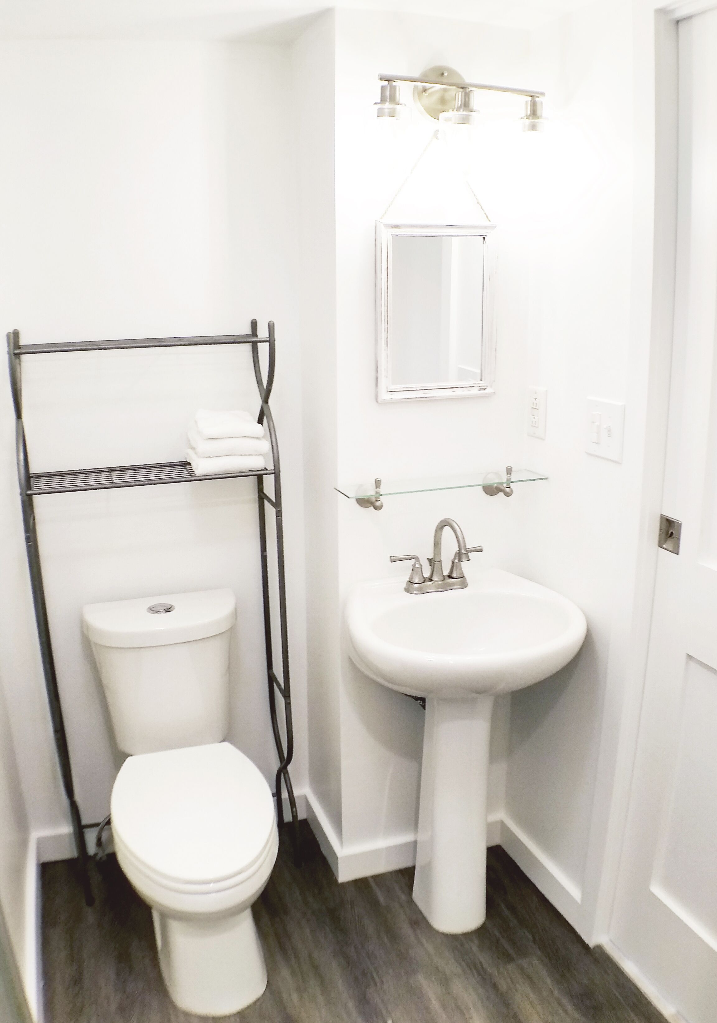 A small, white bathroom with a toilet, a sink, and a towel rack.
