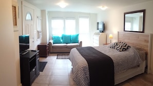 A bedroom with a bed, a TV, a sofa, and a desk.