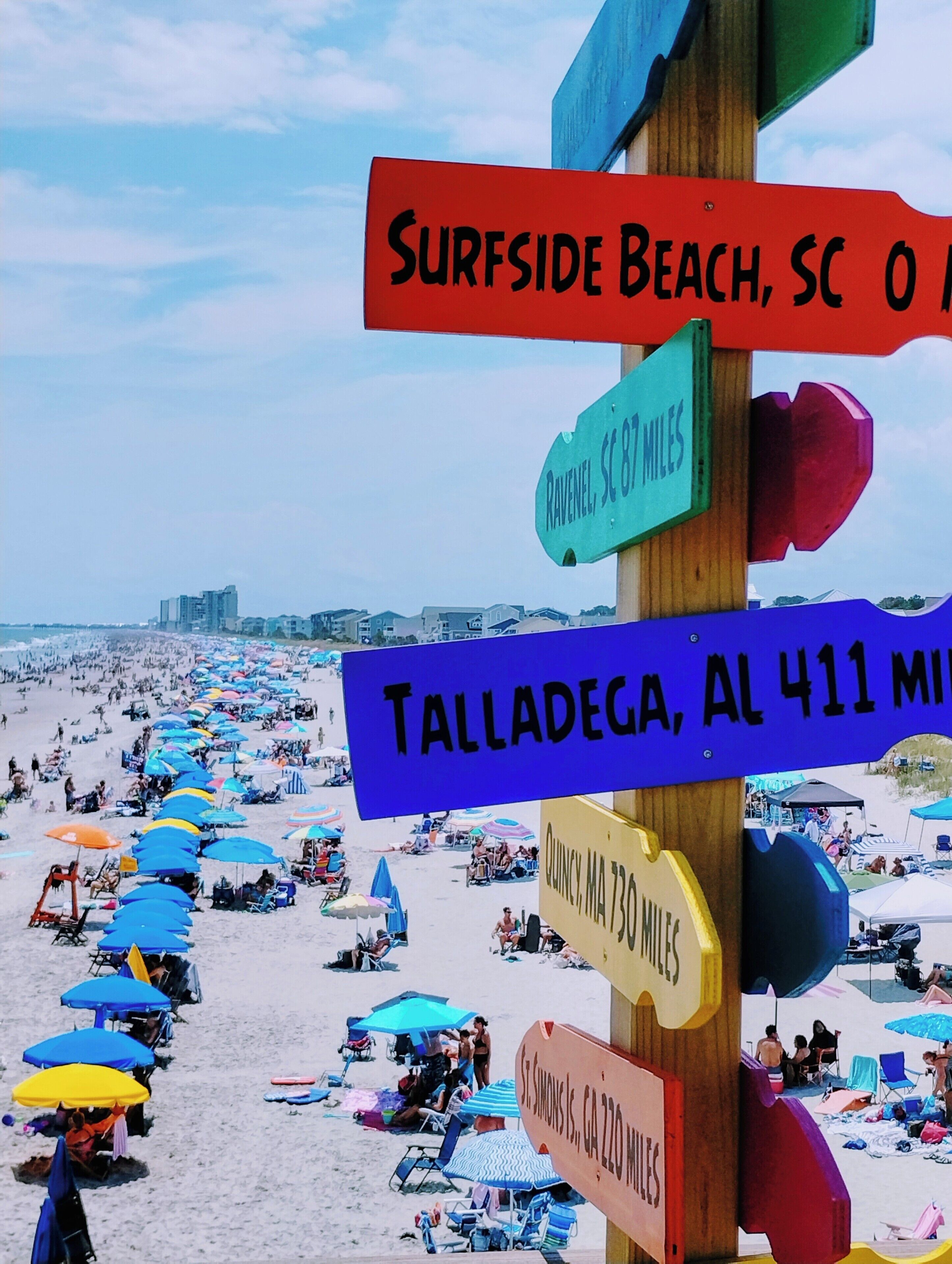 Een strand met richtingaanwijzers die afstanden naar verschillende locaties aangeven.