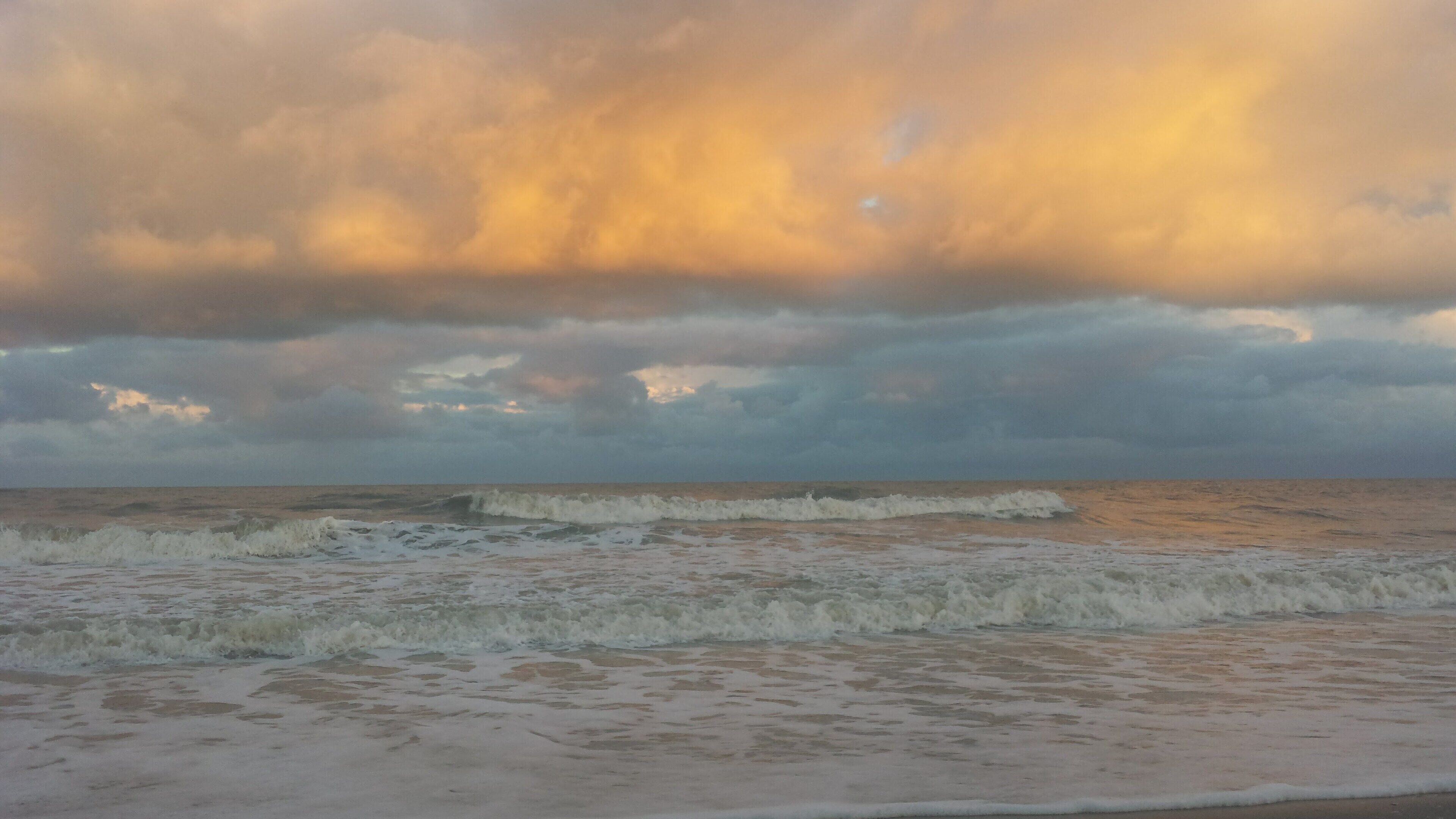 A beach with waves and a cloudy sky.