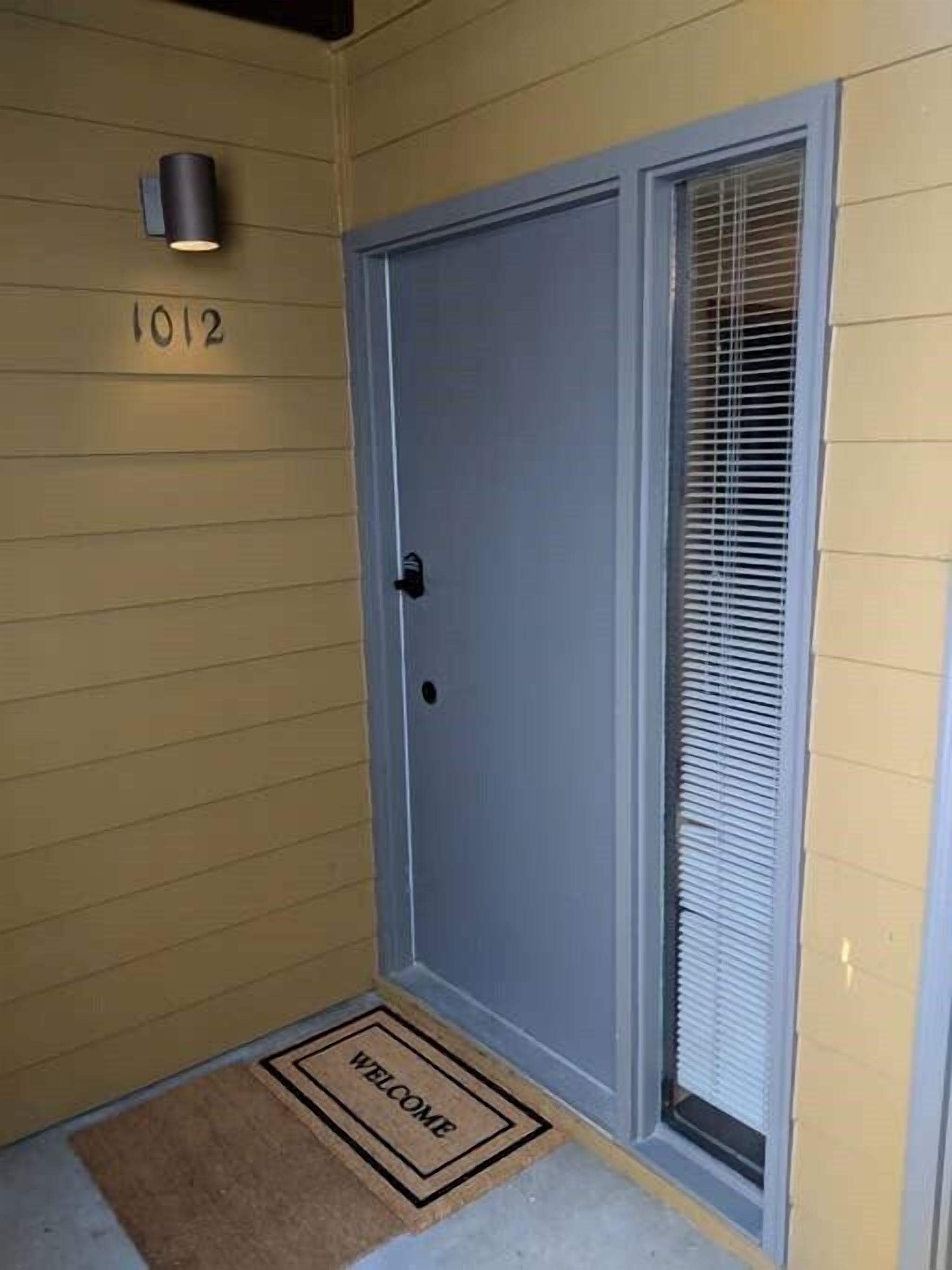 A door with a number '1012' above it, a doormat with 'WELCOME' written on it, and a window with blinds.