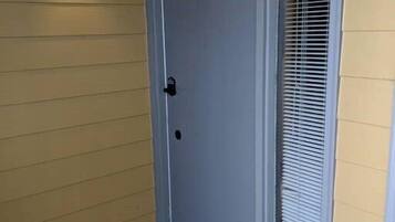 A door with a number '1012' above it, a doormat with 'WELCOME' written on it, and a window with blinds.