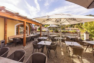 Un patio al aire libre con mesas, sillas, sombrillas y una pérgola de madera.