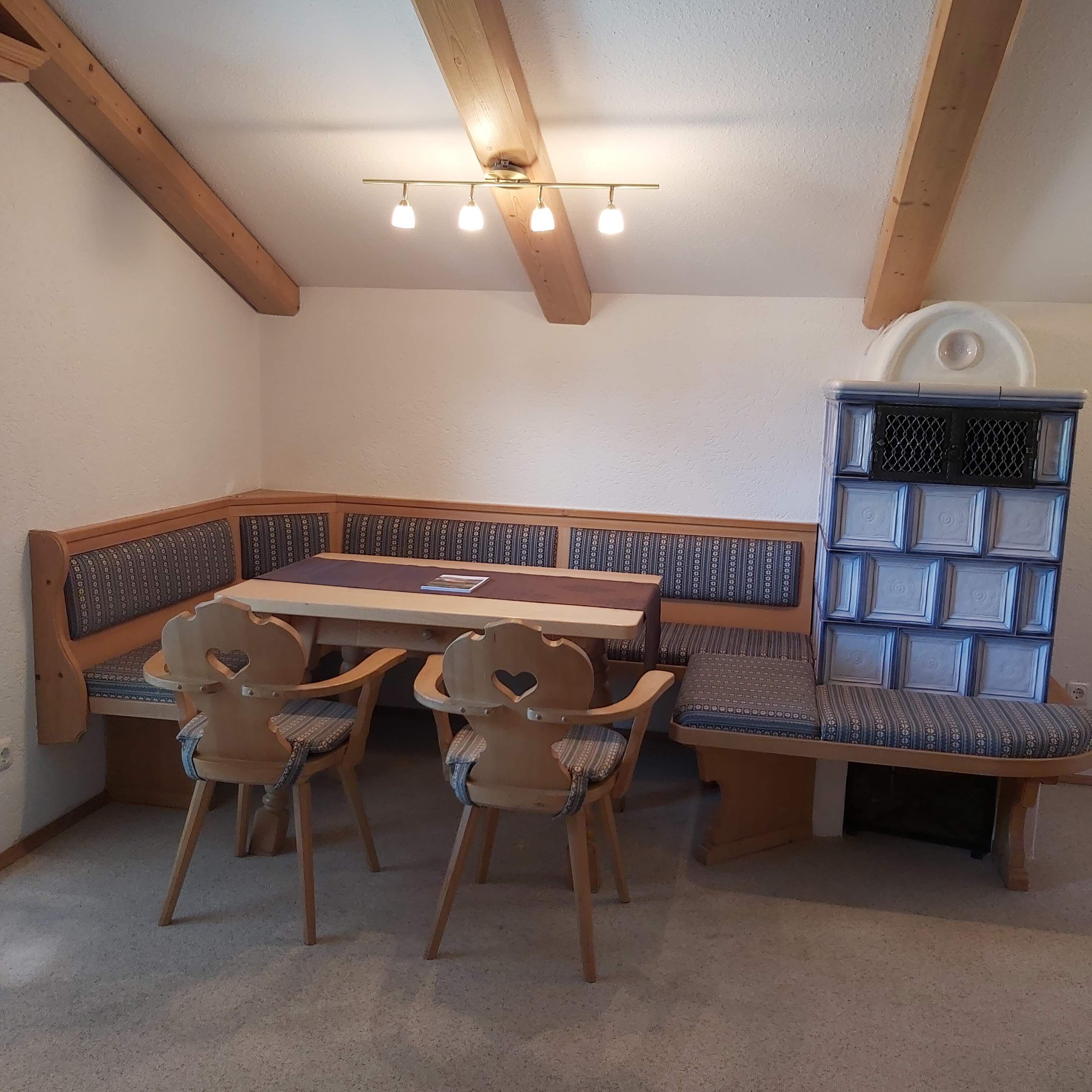 A dining area with a wooden table and bench seating, a ceiling fan, and a built-in bookshelf.