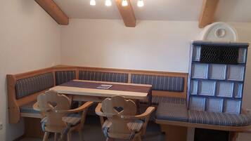 A dining area with a wooden table and bench seating, a ceiling fan, and a built-in bookshelf.
