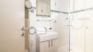 A modern bathroom with a glass shower enclosure, a white sink, and a mirror above the sink.