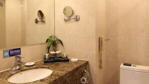 Un baño con lavamanos de mármol, un espejo, un inodoro y una planta pequeña en el mostrador.
