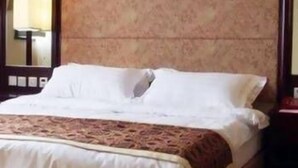 Una cama bien hecha con sábanas blancas y un plaid estampado.