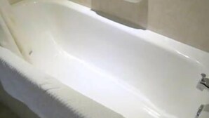 Una bañera blanca estándar con un jabonera integrada y un solo grifo.