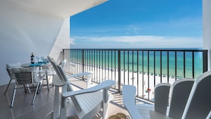 A balcony with a view of the beach, a table with chairs, and a bottle of wine. - BEACHFRONT-9th floor view, recently updated-avail Sept 7-12, 19-23, Oct 18-25 (Destin)
