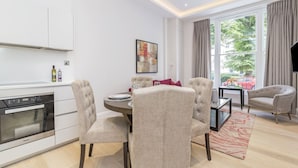 A modern living room with a dining area, a kitchen with a built-in oven, and a large window with curtains. - 3b Imperial (London)