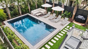 Piscina rectangular con un deck alrededor, sillas de descanso y sombrillas.