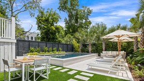 Un patio trasero con piscina, mobiliario exterior y césped bien cuidado.