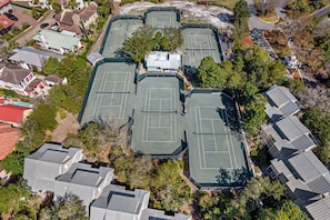 Eine Vogelperspektive auf eine Wohngegend mit mehreren Tennisplätzen, umgeben von Häusern und Bäumen.